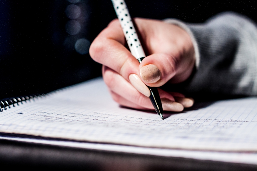 Uma mão a tirar notas sobre um caderno: os estudantes são das populações mais vulneráveis ao stress | Foto: Pexels
