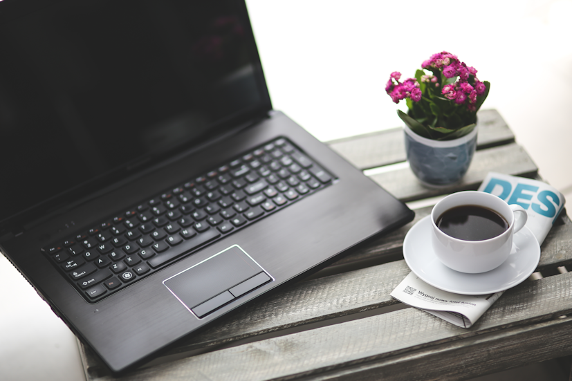 Um computador, uma revista e uma chávena de café: aproveite um momento de relaxamento para pesquisar um pouco sobre o Reiki | Foto: Pexels
